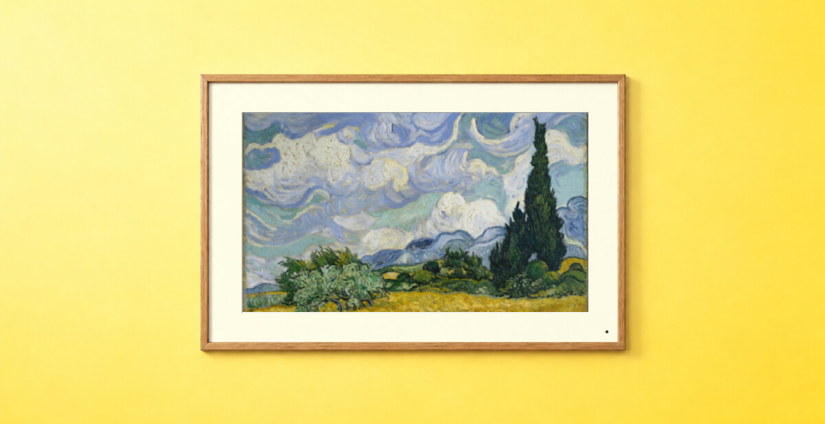 Pixdook digital art frame displaying Van Gogh's Wheat Field with Cypresses on a yellow wall